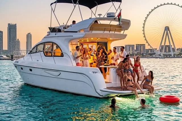 The yacht lit up at sunset beside Ain Dubai