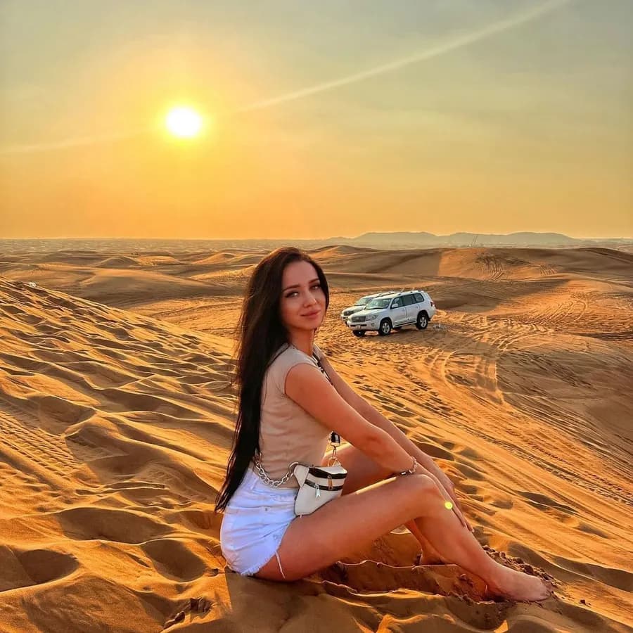 Guest sitting on the dunes with the 4x4 behind