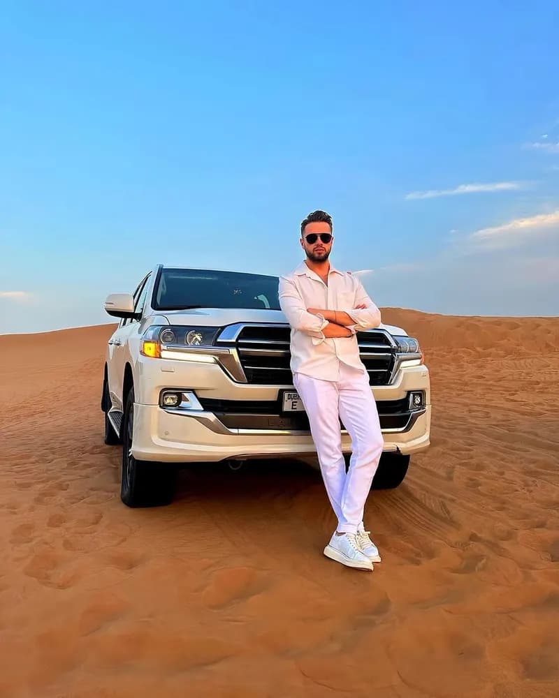 Guest posing beside the white 4x4 under a blue sky