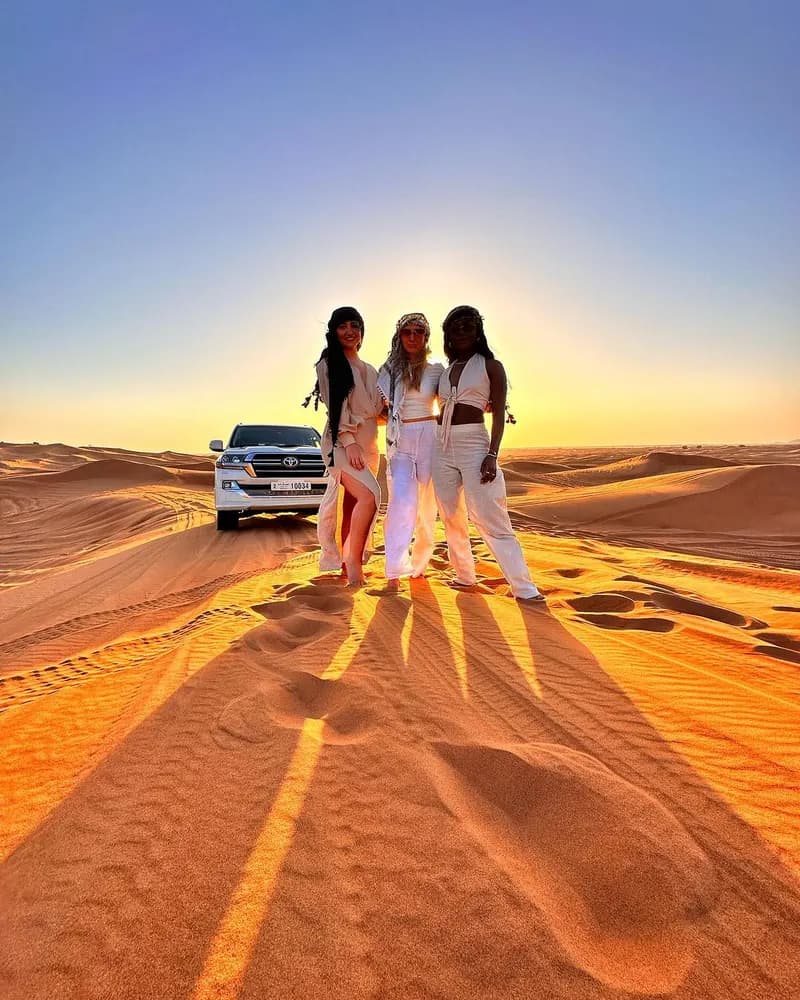 Friends standing together on the dunes at sunrise