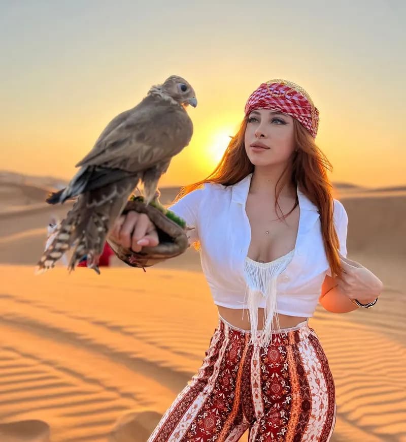 Guest posing with a falcon in the desert