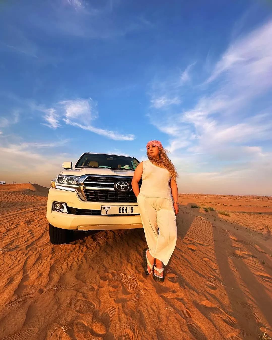 Guest leaning on the 4x4 under a blue desert sky