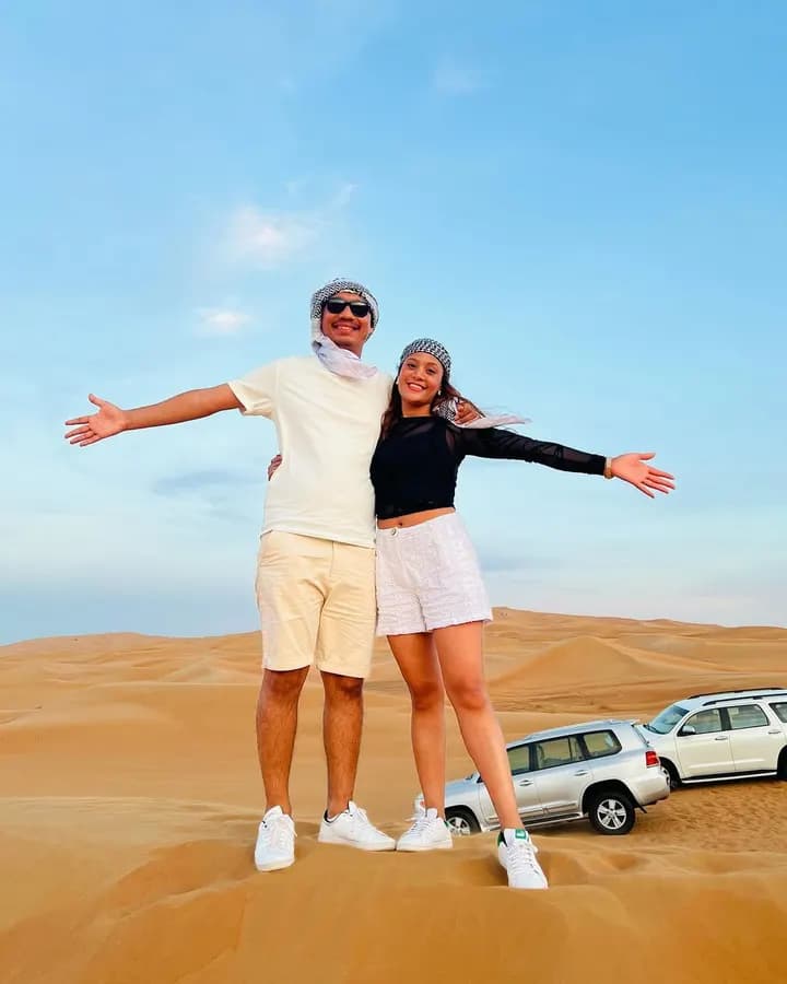 Couple celebrating on the dunes beside the 4x4