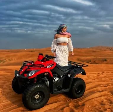 Guest standing on a red quad bike in the desert