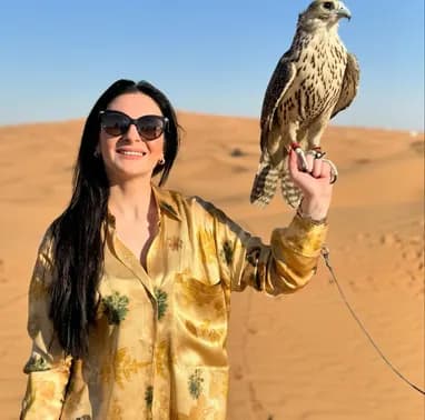 Guest posing with a falcon in the desert