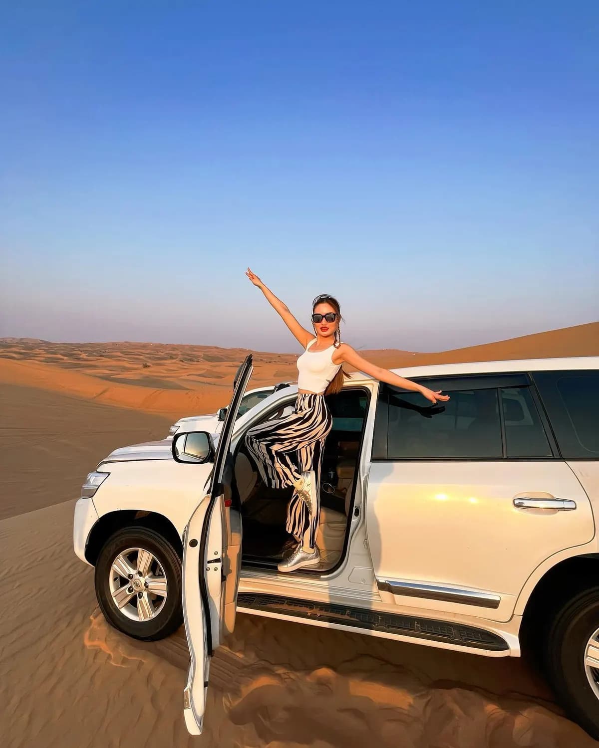 Guest posing at the door of a safari 4x4 on the dunes