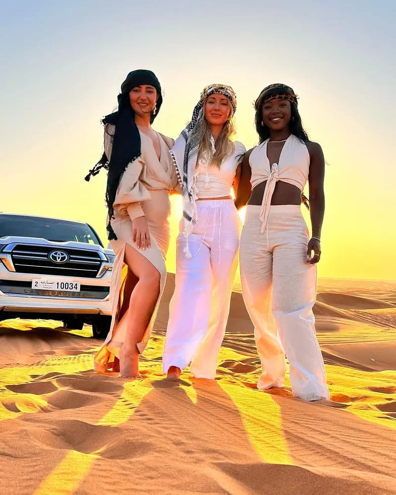 Friends posing beside the safari vehicle at sunset