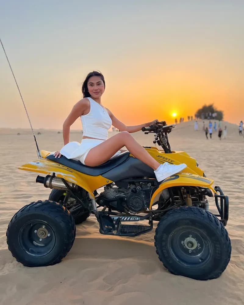 Guest posing on a yellow quad bike at sunset