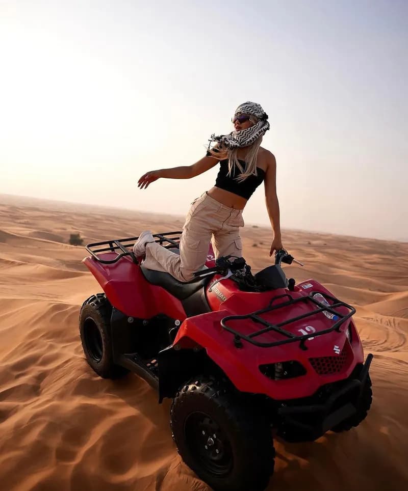 Guest standing on a red quad bike in the desert