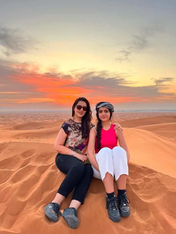 Friends sitting together on the dunes at sunset