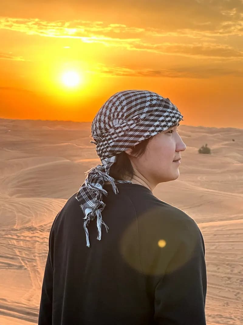Guest in a keffiyeh watching the desert sunset