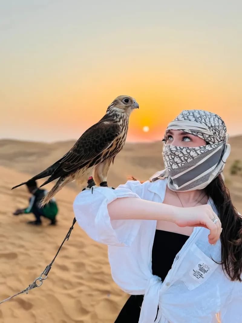 Guest posing with a falcon in the desert