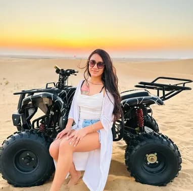Guest seated beside a quad bike on the dunes