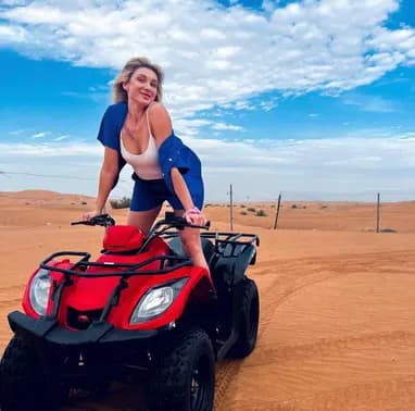 Guest on a red quad bike under a blue sky