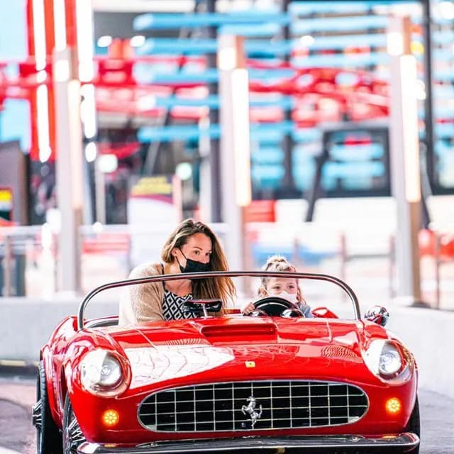 Family in a classic red Ferrari at the park