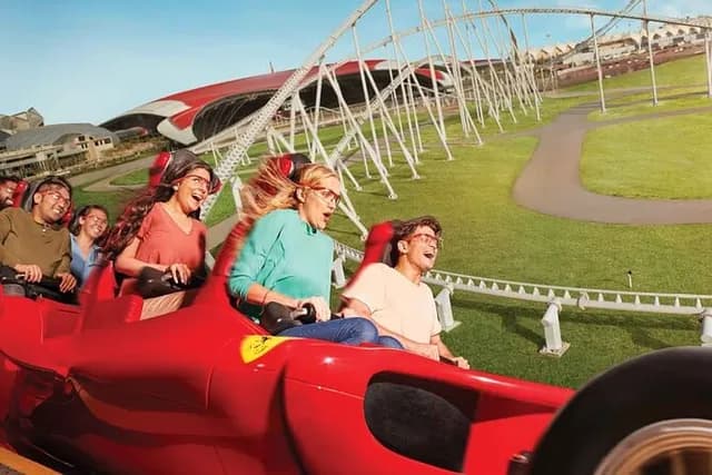 Three riders in a Ferrari-styled ride car