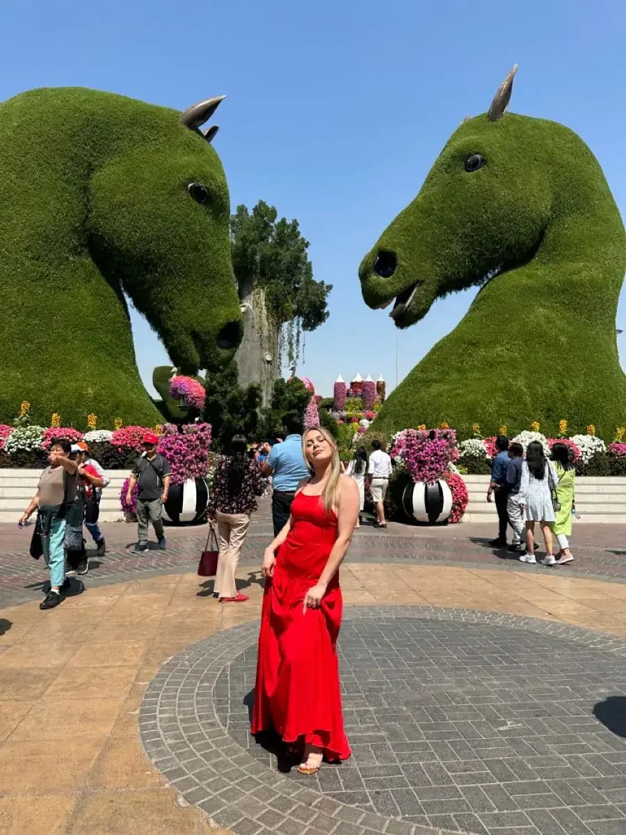 Guest posing between the garden's horse topiaries