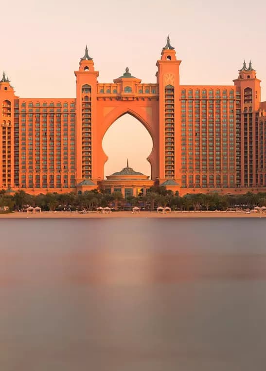 Atlantis The Palm hotel and its grand arch seen across the water at sunset