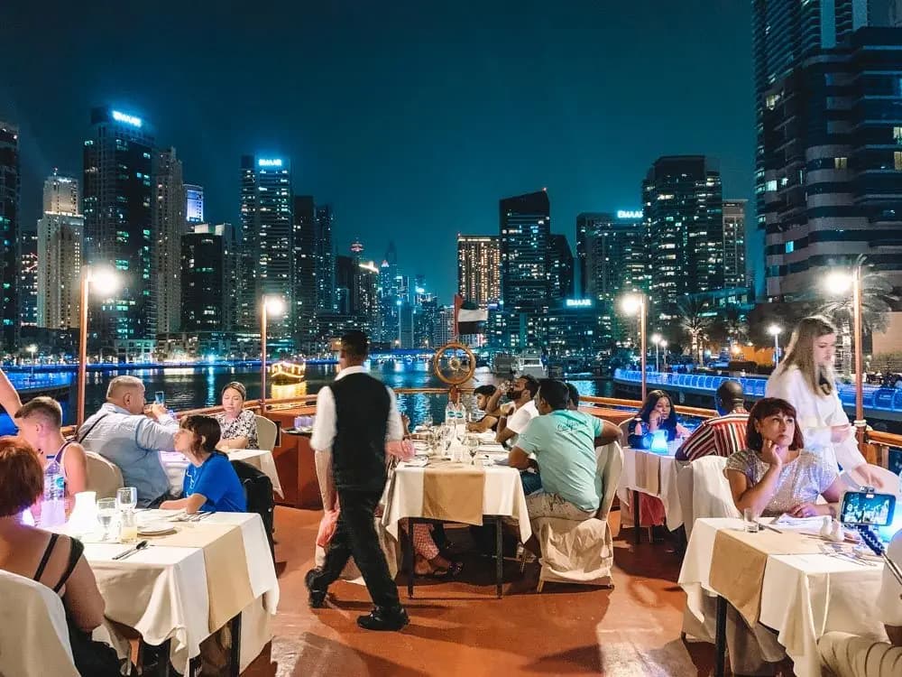 Guests dining on the open deck with the skyline behind