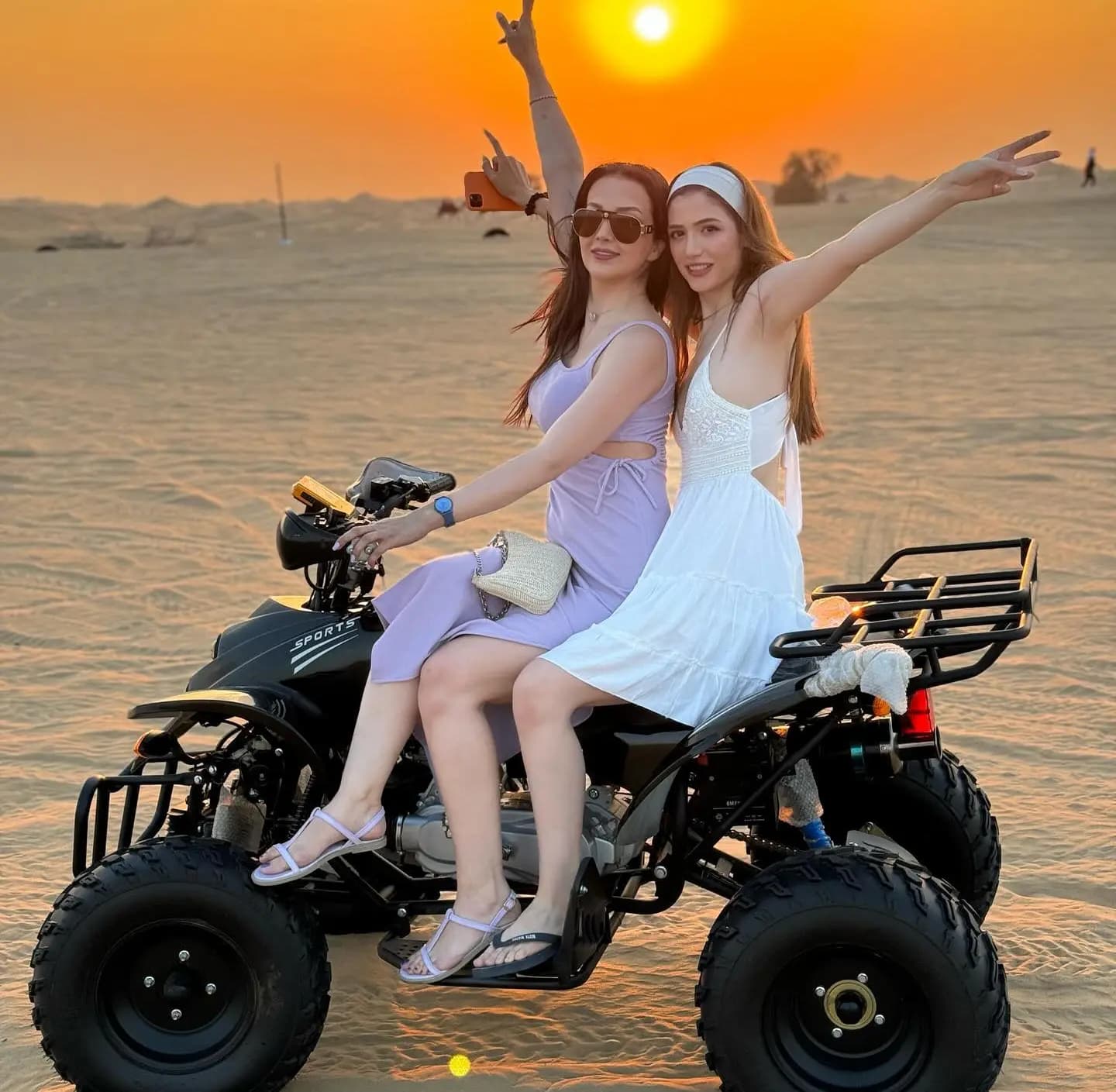 Two guests on a quad bike waving in the desert