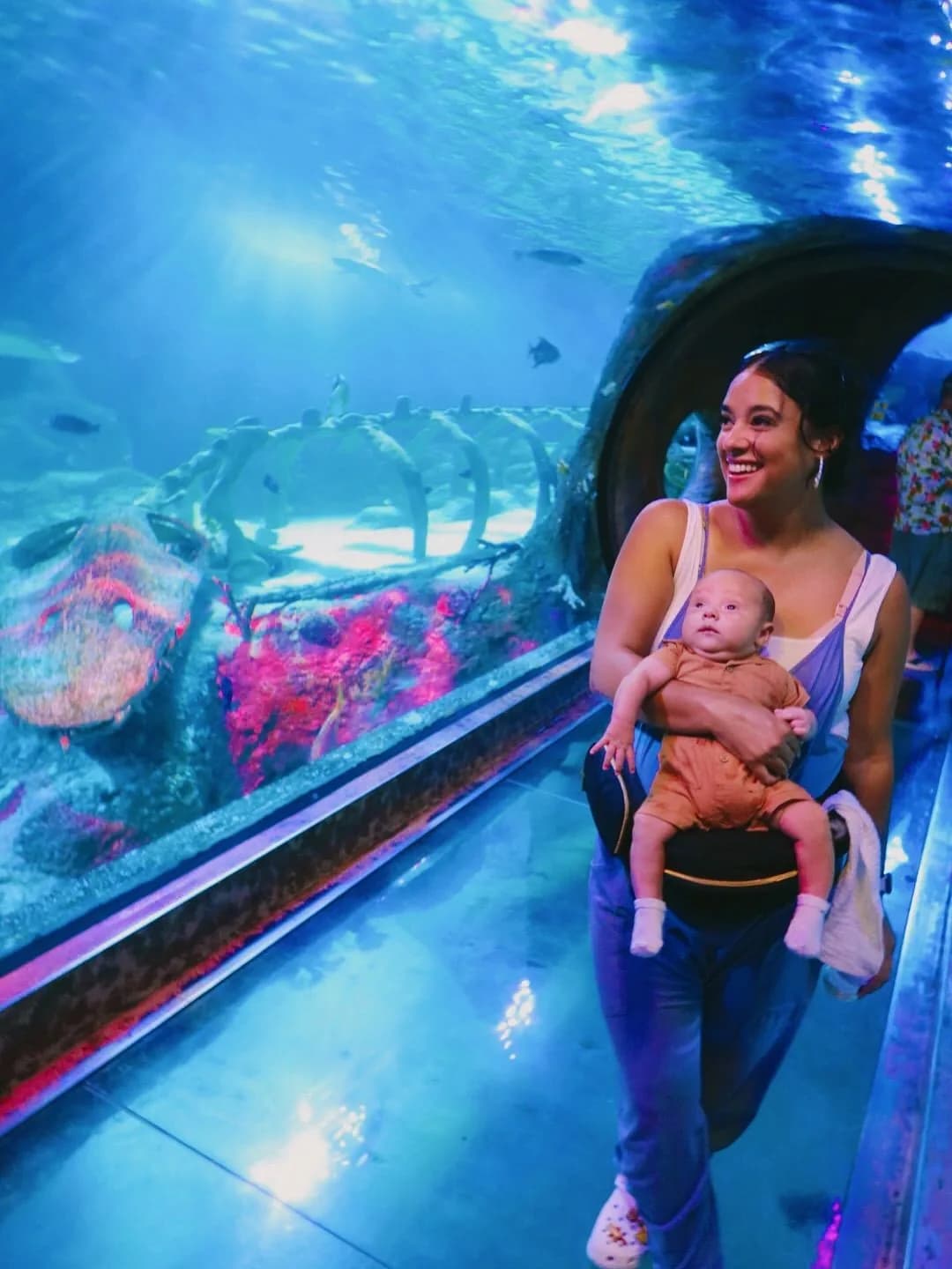 Parent carrying a baby through the aquarium tunnel